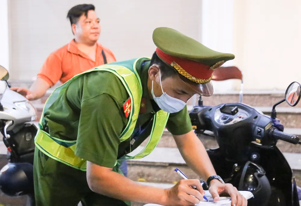 Công an lập biên bản xử phạt hành chính điểm trông giữ xe tự ý nâng giá vé niêm yết. Ảnh PHI HÙNG