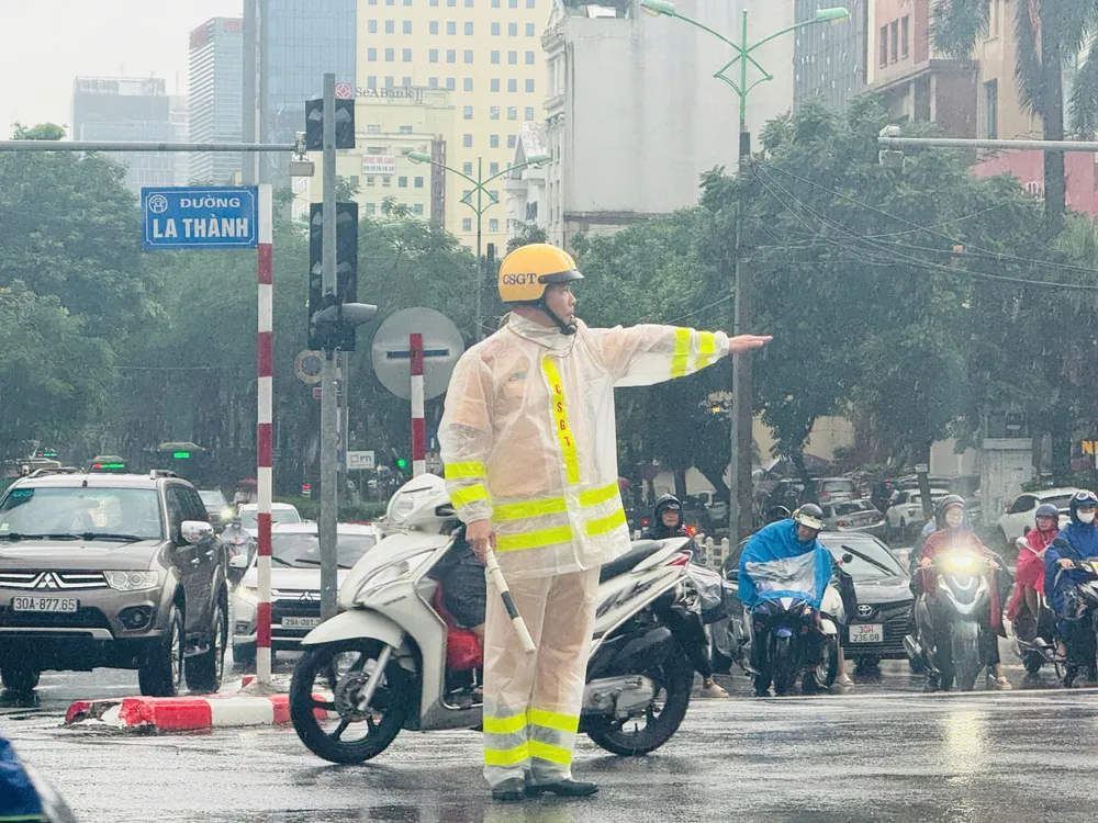 CSGT phân luồng trên đường Đê La Thành trong cơn mưa nặng hạt sáng 26-8. Ảnh: CA