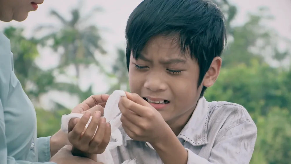 Cậu bé Thành cầm kỷ vật ba mẹ ruột. Ảnh: SV