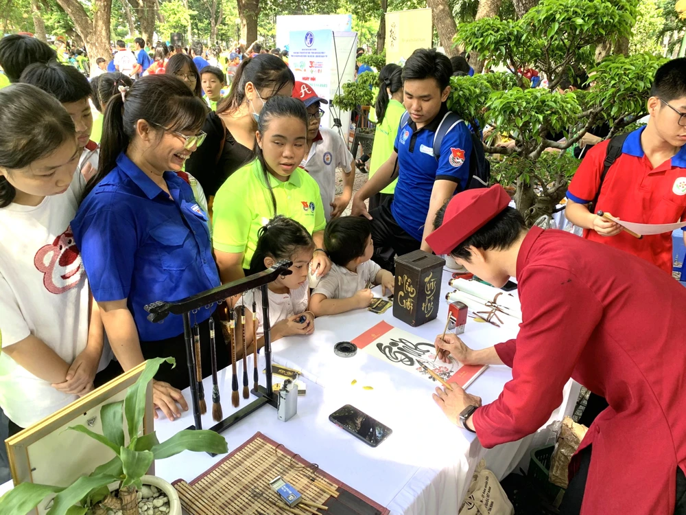 Nhiều em thiếu nhi say mê khi xem ông đồ viết thư pháp.