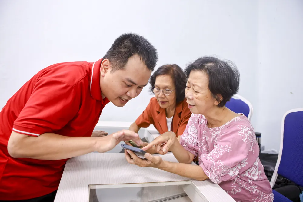 Anh Nguyễn Đăng Khoa hướng dẫn các cụ thao tác trên điện thoại. Ảnh: NGUYỆT NHI hoc-dung-dien-thoai-10.jpg