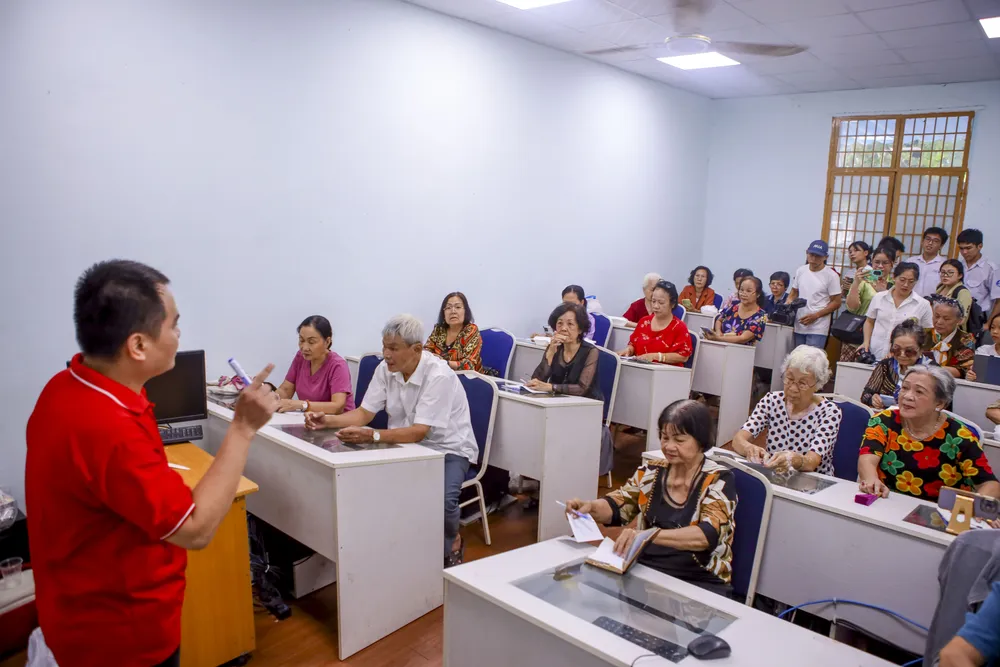 Những người tham gia học dùng điện thoại đa phần tuổi từ 60 đến 90. Nguyễn Đăng Khoa, trong vai trò người hướng dẫn, liên tục hỏi các cụ: “Có bác nào đăng nhập thành công chưa ạ?”. Một cụ bà vui vẻ giơ cao điện thoại khoe thành quả với thầy giáo. Ảnh: NGUYỆT NHI Khi người cao tuổi học dùng điện thoại để đặt xe, chuyển tiền, chơi tiktok