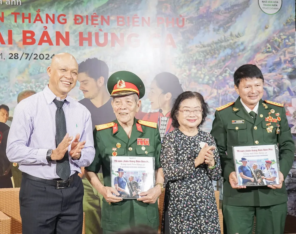 Nhiếp ảnh gia Nguyễn Á (bìa trái) cùng bà Trương Mỹ Hoa, Nguyên phó Chủ tịch, nước gửi tặng sách cho hai khách mời đặc biệt của chương trình là Đại tá Hoàng Ngọc Thương và Đại tá Đoàn Hoài Trung (từ trái qua). Ảnh: PHƯỚC HUỆ Triển lãm ảnh 70 năm Điện Biên Phủ của Nhiếp ảnh gia Nguyễn Á