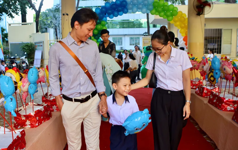 Hai vợ chồng anh Lâm Sư Toàn (quận 8) đưa con vào lớp 1. Ảnh: NGUYỆT NHI Trường học TP.HCM rộn ràng ngày hội “Em vào lớp 1”