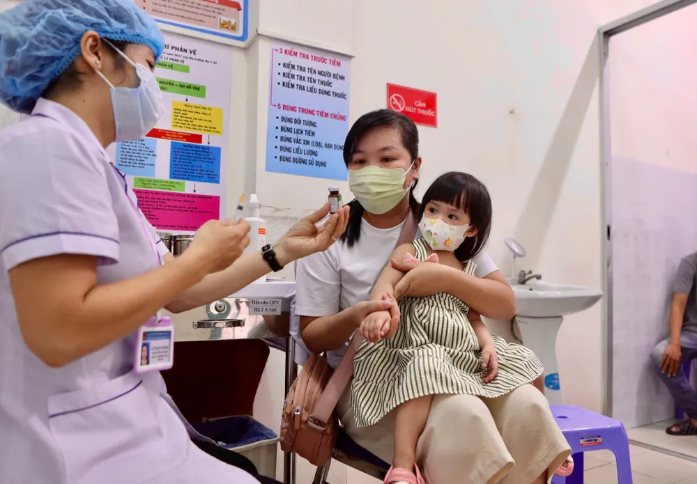 Chị Lê Thị Hồng Cúc nghe nhân viên y tế tư vấn về vaccine trước khi tiêm cho con. Ảnh: NGUYỆT NHI tiem-vaccine-soi (8).jpg