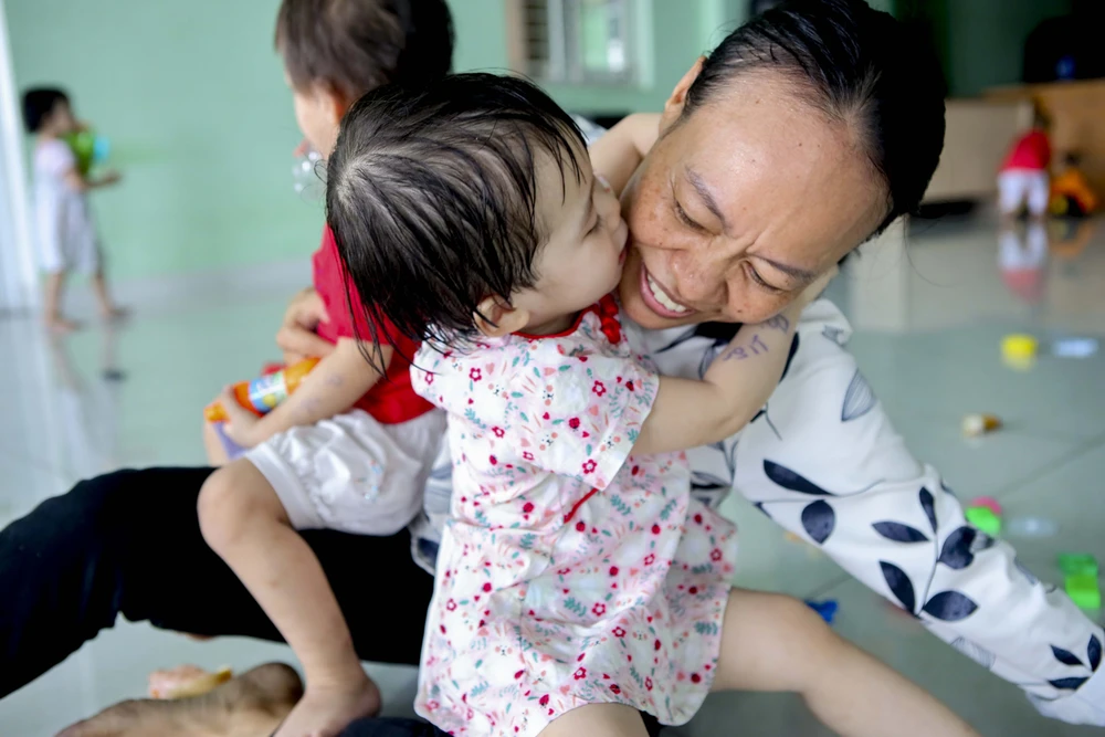 Em bé ôm hôn bà Trần Thị Hiên (50 tuổi) nhân viên của trung tâm. Ảnh: NGUYỆT NHI Ngôi nhà mới của những em bé mái ấm Hoa Hồng
