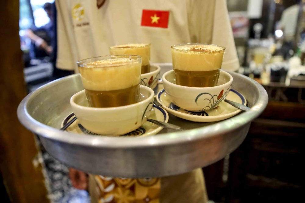 Đại biểu quốc tế mặc dài thưởng thức cà phê trứng