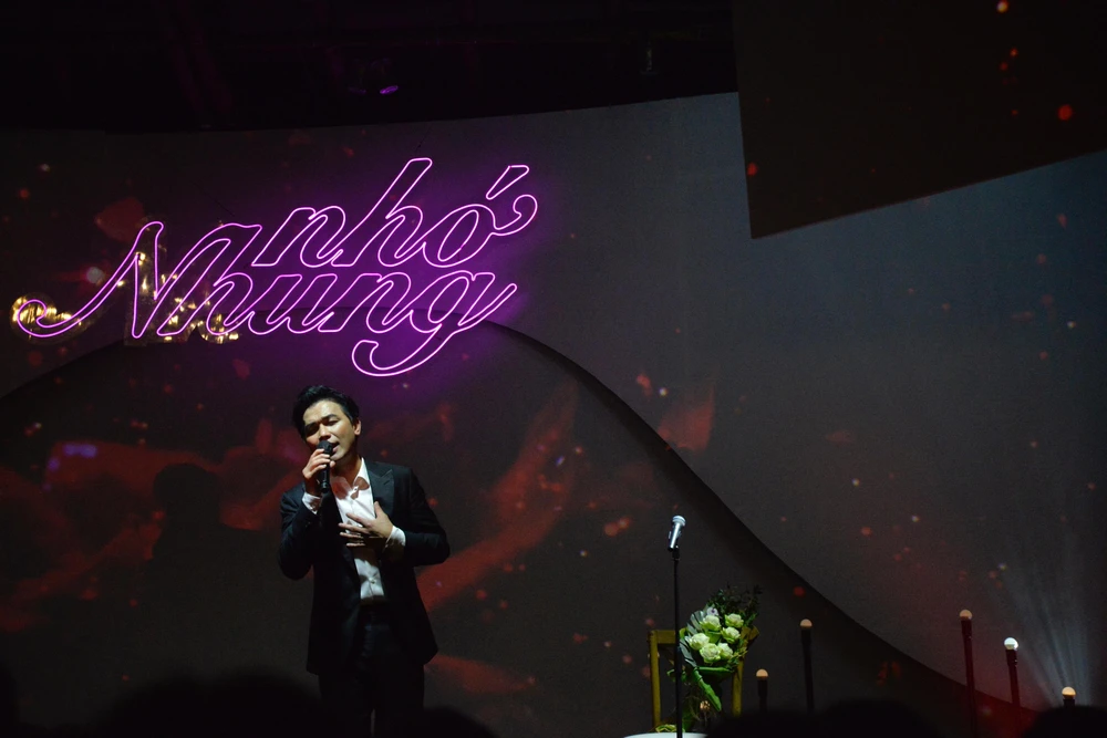 Mạnh Quỳnh say sưa hát. Bên cạnh anh là chiếc ghế nhỏ được đặt trang trọng có micro và bó hoa tươi như hình ảnh Phi Nhung luôn hiện hữu