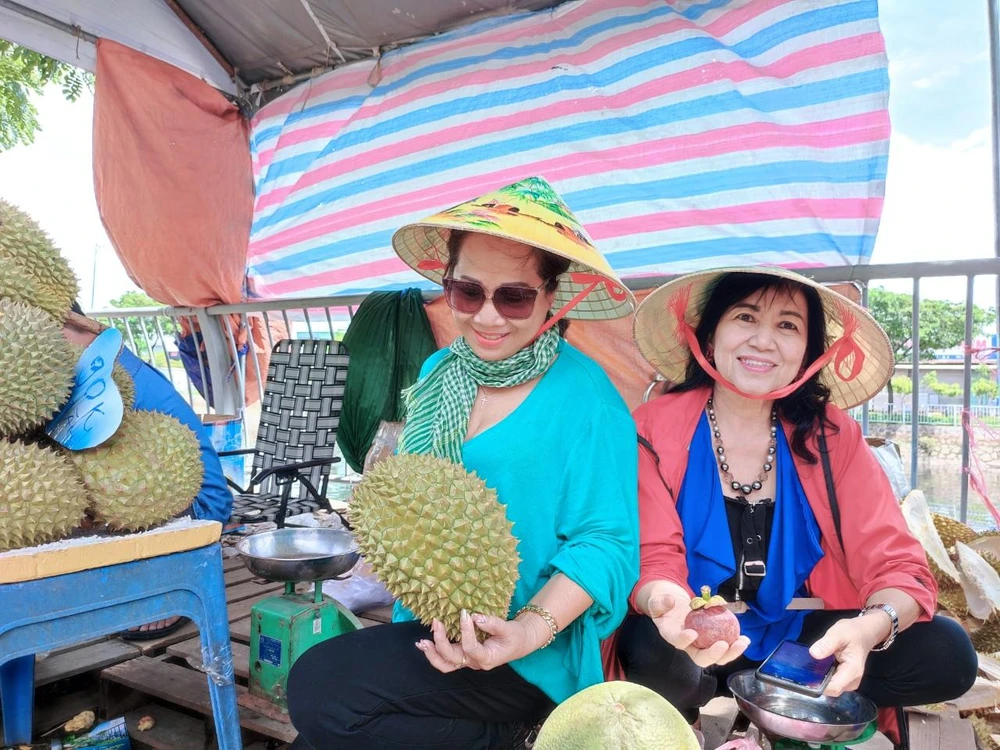 Chị Nhũ Hương khách mua hàng khen sầu khen, nhiều trái cây ở lễ hội tươi ngon nên rủ bạn tới cùng mua. Ảnh: NGUYỄN TRÀ