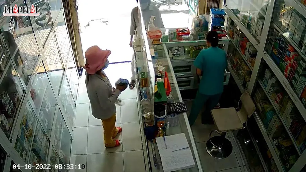 Người phụ nữ lấy hai hộp thuốc cho vào túi mà chủ hiệu thuốc không hay biết. Ảnh chụp từ clip