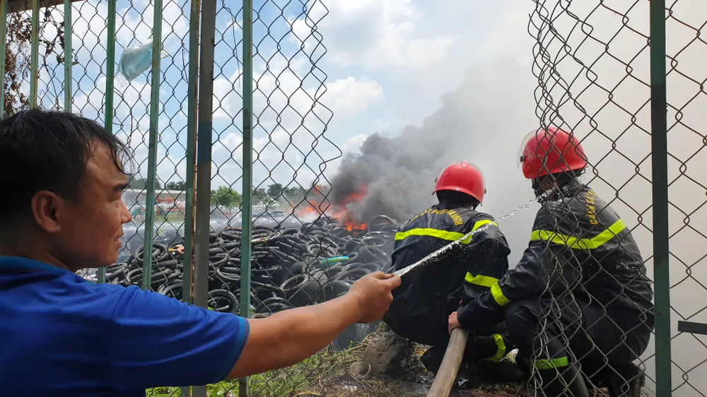 Người dân hỗ trợ xịt nước vào người các chiến sĩ CS PCCC để hạ nhiệt. Ảnh: NT