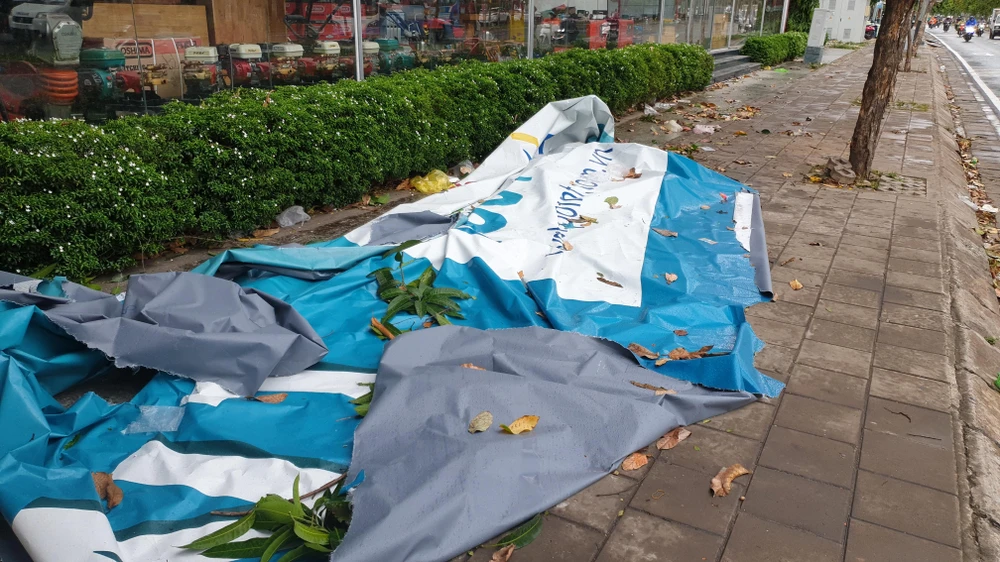 Tấm bạt ở biển quảng cáo bị gió cuốn bay hàng trăm mét. Ảnh: NT