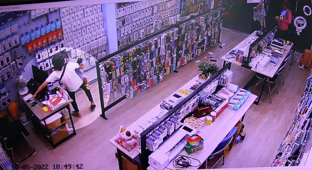 Trong lúc Thịnh hỏi mua ốp lưng, Thúy lấy trộm điện thoại của nhân viên. Ảnh chụp từ clip