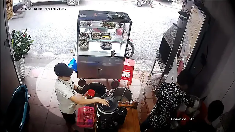 Người phụ nữ tranh thủ chủ quán quay lưng làm cơm thì lấy điện thoại. Ảnh chụp từ clip