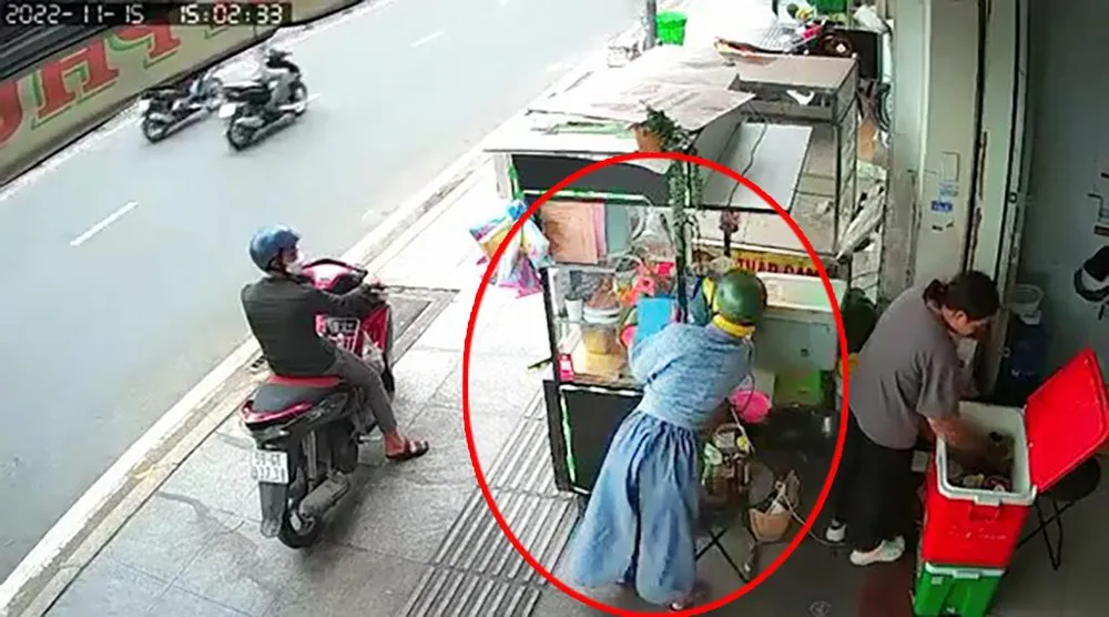 Người phụ nữ dàn cảnh lấy trộm chiếc điện thoại ngay sau lưng nữ nhân viên. Ảnh chụp từ clip