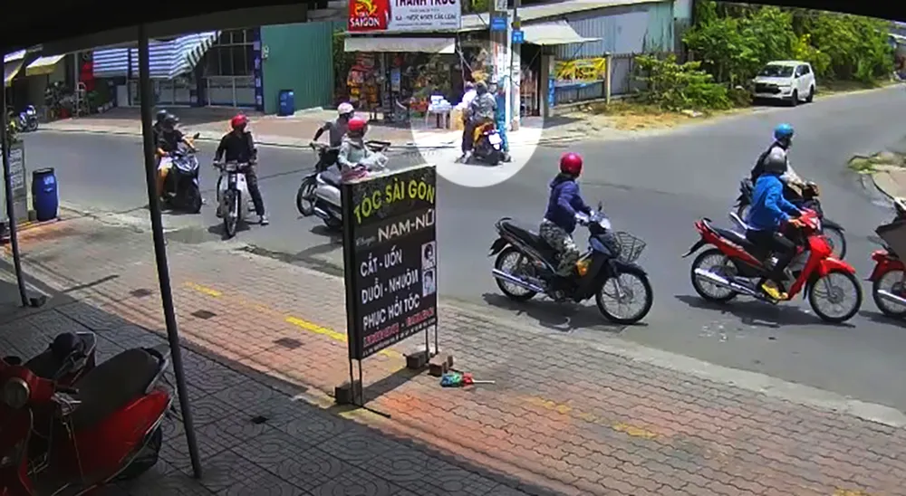 Người mặc đồ dân quân tự vệ dùng gậy đánh vào đầu nam thanh niên chạy xe máy. Ảnh cắt từ clip