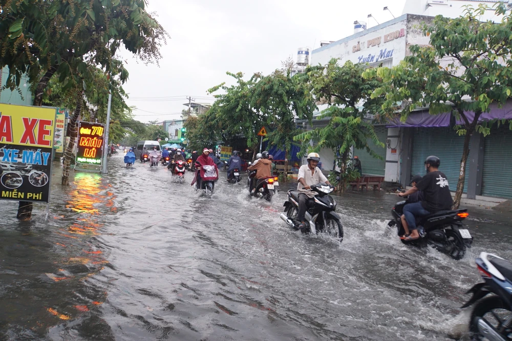 Trên đường Song Hành, quận 12 nước ngập cục bộ kéo dài hàng chục mét khiến việc di chuyển của người dân vào giờ cao điểm gặp khó khăn.
