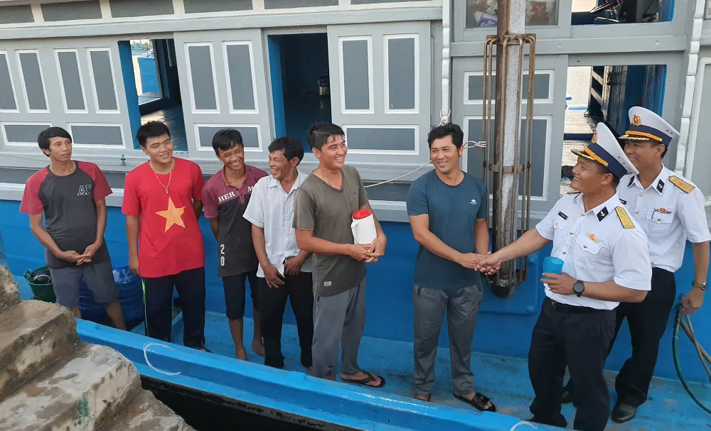 Thiếu tá Trần Cộng Hòa và đại úy Vũ Hoàng Tùng gặp gỡ các ngư dân neo đậu tại âu tàu trên đảo Trường Sa hỏi thăm họ về tình hình đánh bắt, có cần giúp đỡ gì không. Ảnh: NT