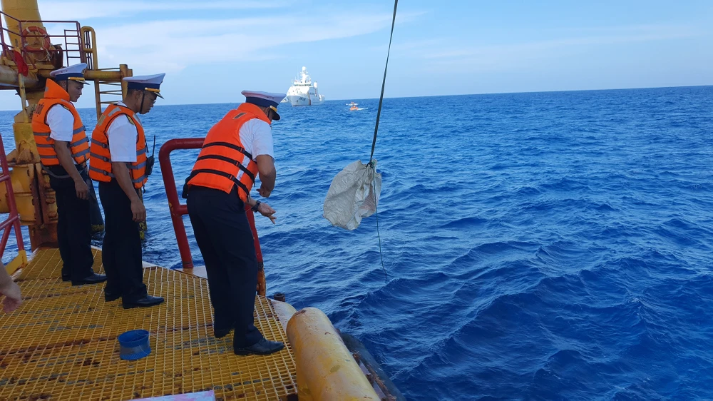 Việc đưa hàng hóa lên nhà dàn cũng gặp không ít khó khăn, do túi chứa hàng bị gió thổi bay. Lực lượng trên nhà dàn phải dùng dây câu để đôi, móc lại. Ảnh: NT