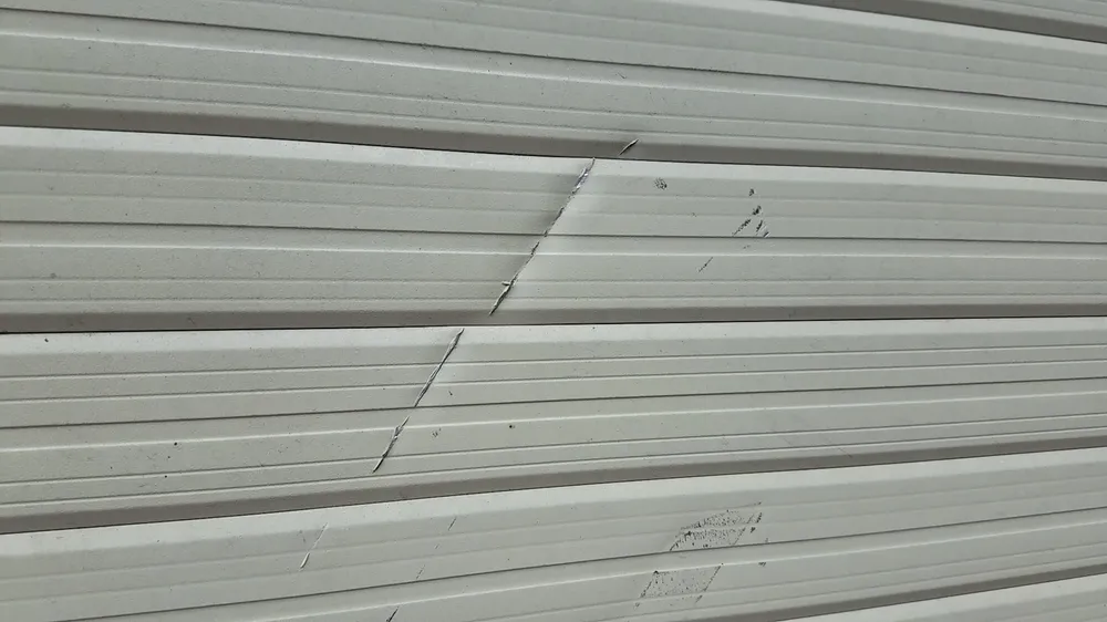 Cửa cuốn nhà anh T bị chém hư hỏng, cửa kính bên trong bị chém bể nát. Ảnh: HT