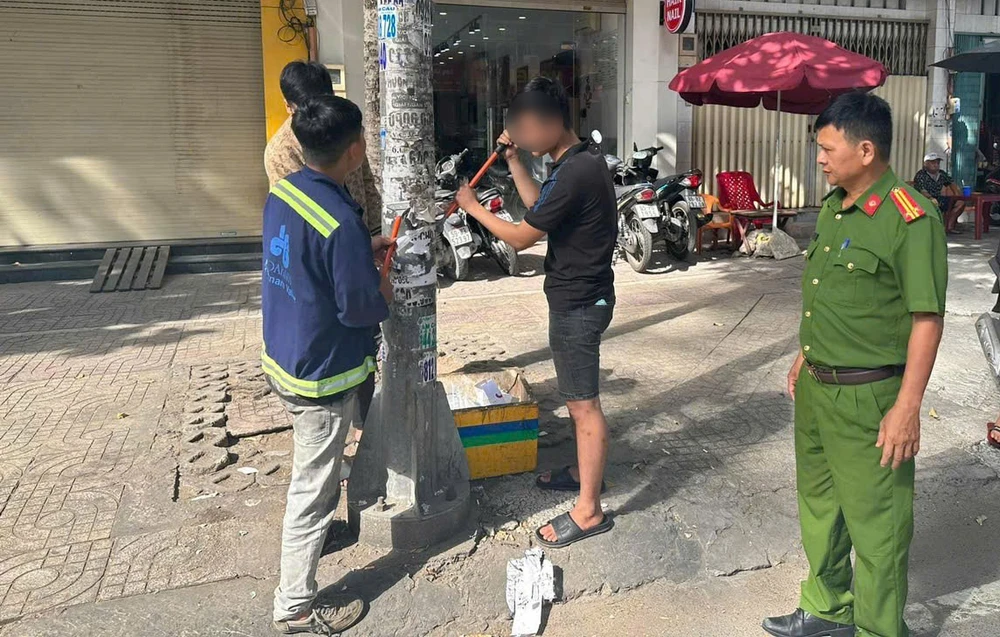 Cơ quan chức năng yêu cầu ba người này phải làm sạch các cột điện, cửa nhà dân trên địa bàn. Ảnh: HT dang-dan-quang-cao-chui-bi-to-363-cong-an-quan-5-phat-hien-9747.jpg