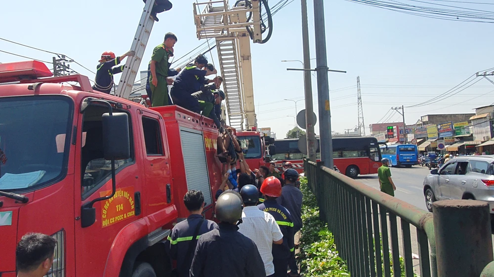 Cảnh sát đưa nam thanh niên xuống đất an toàn. Ảnh: NT Cảnh sát phong tỏa Quốc lộ 22, cứu thanh niên nghi 'ngáo đá' leo cột đèn