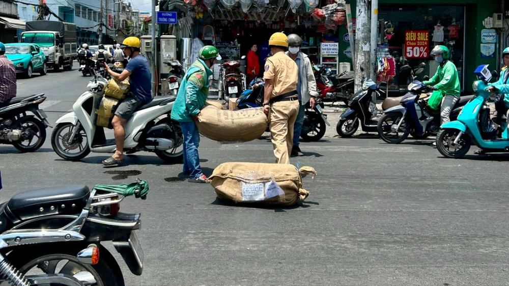 Phát hiện người dân làm rơi hàng hóa sau va chạm giao thông, cán bộ Đội CSGT-TT, Công an quận Tân Bình đã giúp người dân thu dọn. Ảnh: NDCC Cán bộ CSGT Tân Bình giúp người dân dọn hàng hóa ở Tân Bình