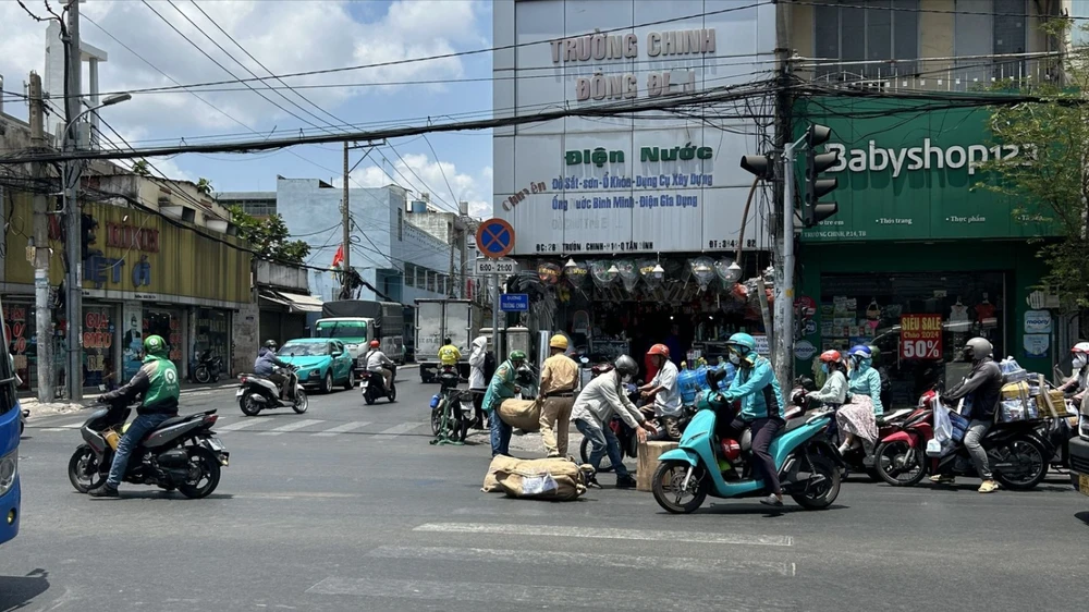 Hành động đầy ý nghĩa của cán bộ CSGT được người đi đường chụp lại. Ảnh: NDCC Cán bộ CSGT Tân Bình giúp người dân dọn hàng hóa ở Tân Bình