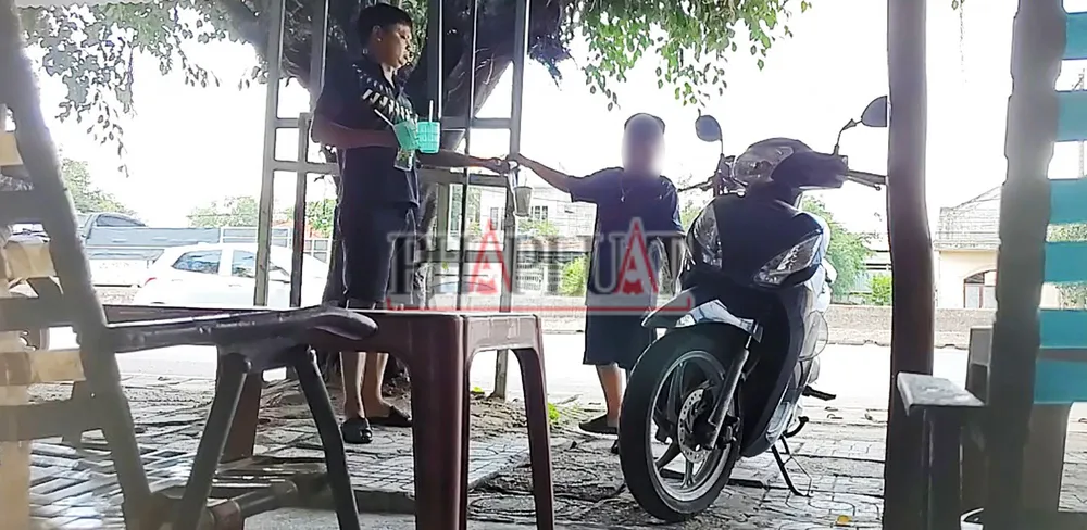 Nguyễn Đình Hưng diễn cảnh đưa nước nhưng thực ra là cảnh giới cho con trai ông Đông phá xe của khách. Ảnh: NHÓM PV Bài 4: Cận cảnh người lớn phối hợp trẻ con phá xe trên Quốc lộ 51