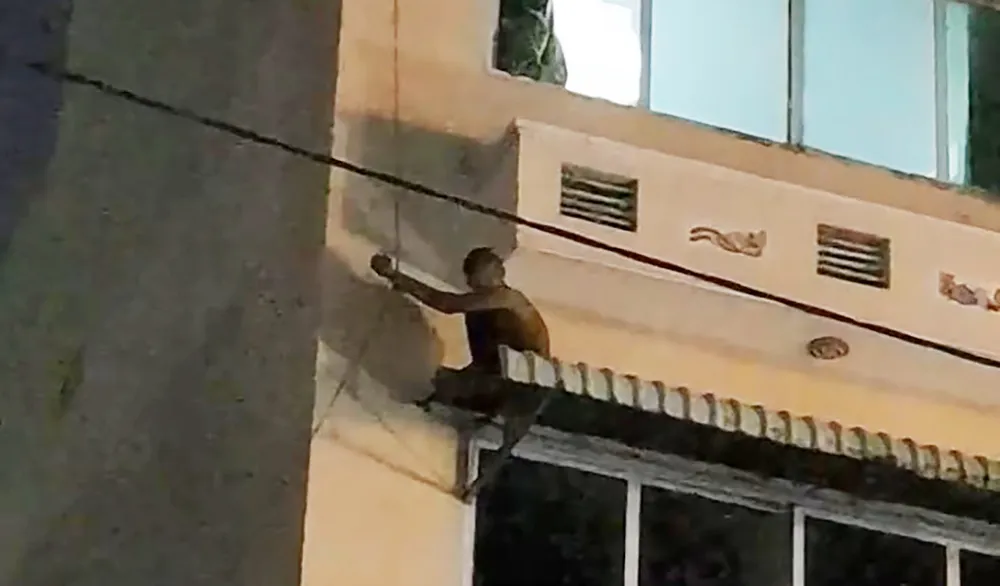 Nam thanh niên ngồi trên mái che của tầng 3 khách sạn. Ảnh: HT Thanh niên nghi ngáo đá, đu dây ở tầng 3 khách sạn như “người nhện”