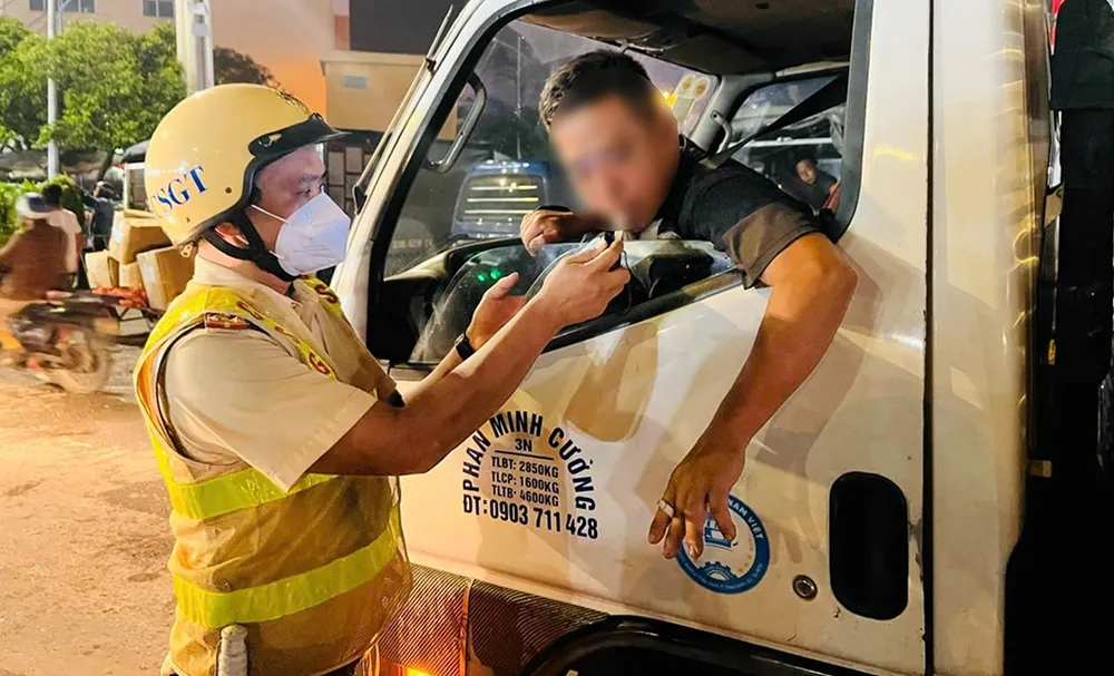 Tổ công tác kiểm tra nồng độ cồn với tài xế xe tải. Ảnh: CA Công an kiểm tra, xử lý xe cơ giới, xe ba bốn bánh tự chế ở Chợ đầu mối Hóc Môn