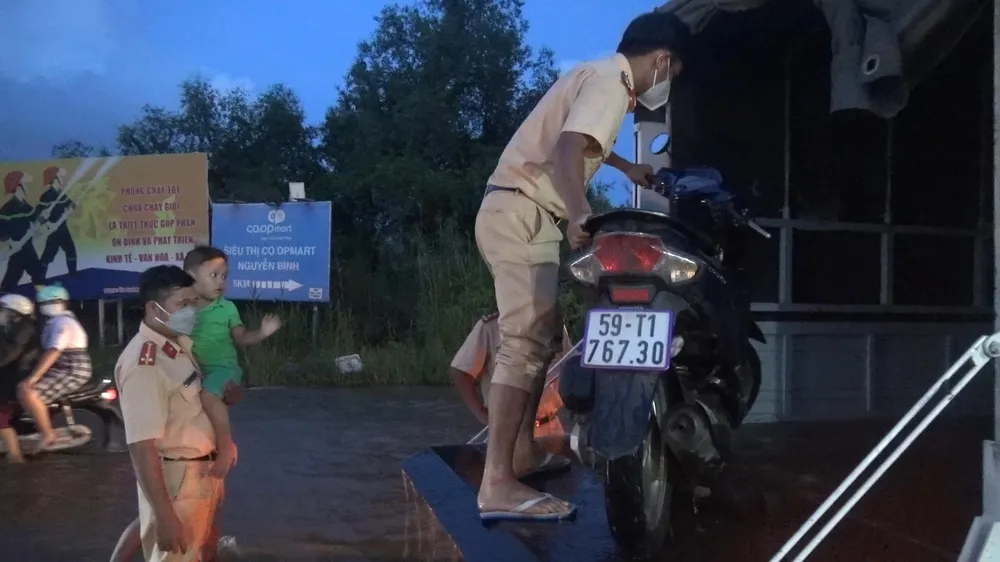 CSGT đưa trẻ em qua đoạn nước ngập. Ảnh: ĐC