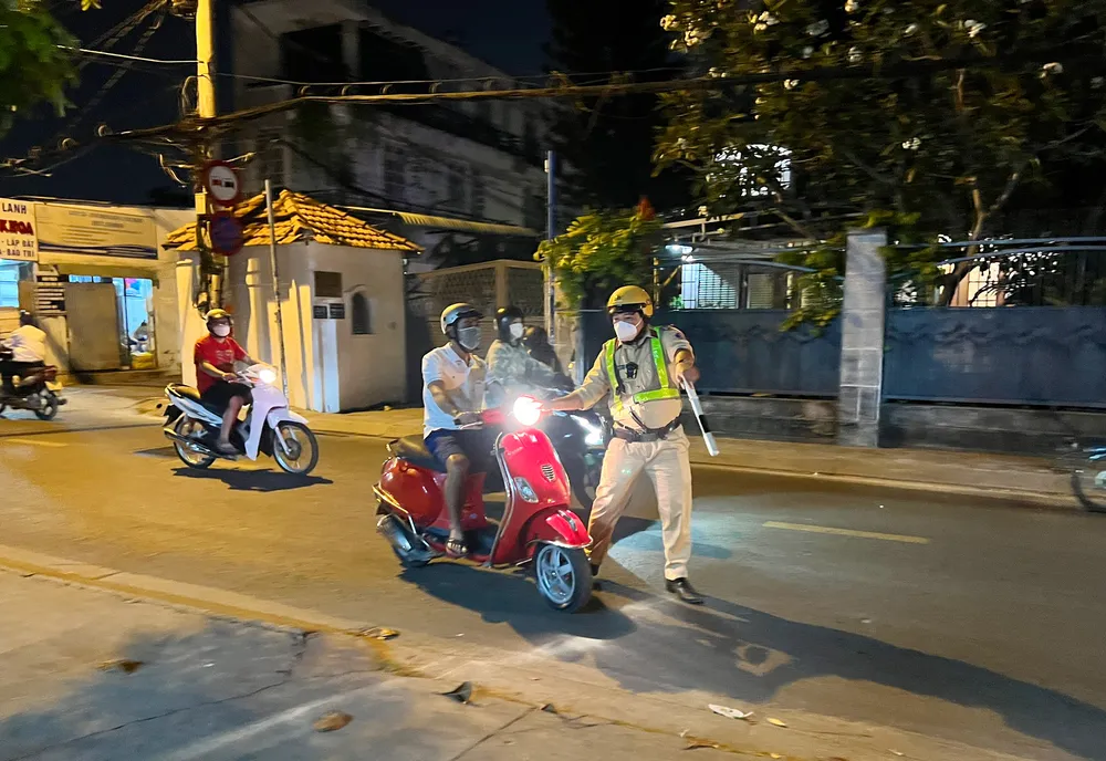 CSGT ra hiệu kiểm tra nồng độ cồn với một người đi xe máy vào tối 30-1. Ảnh: NGUYỄN YÊN