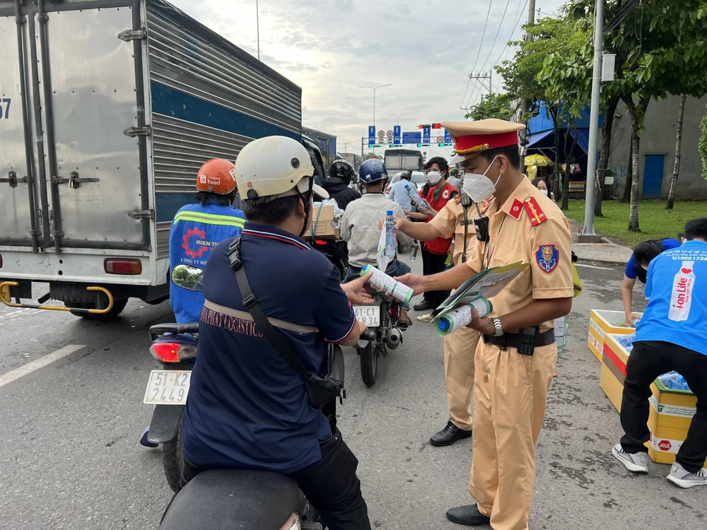 CSGT phát nước suối, tờ rơi tuyên truyền luật giao thông cho người dân.