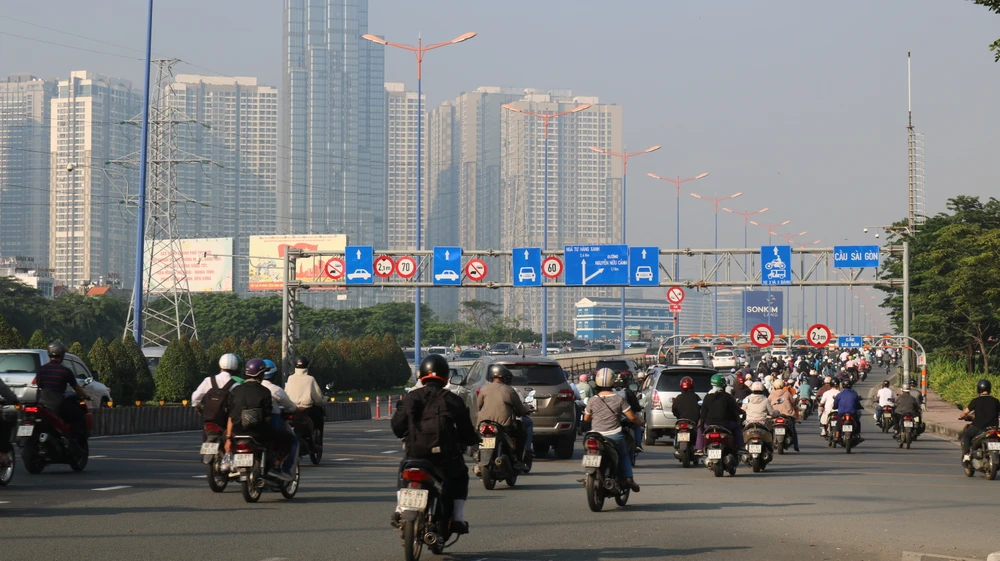 Nhiều xe máy chạy vào làn đường dành riêng cho ô tô trên cầu Sài Gòn. Ảnh: HỒNG THẮM Biển báo cấm được đặt ngay dưới chân cầu, thế nhưng nhiều chủ phương tiện vẫn ngang nhiên vi phạm.JPG