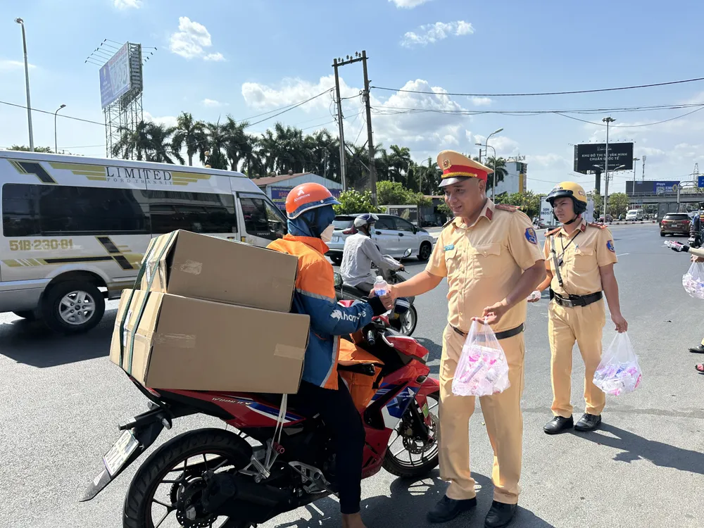 CSGT thuộc Đội CSGT Hàng Xanh phát nước suối, khăn lạnh cho người đi đường vào chiều 26-4. Ảnh: NGUYỄN YÊN csgt-tp-hcm-tuc-truc-24-24-tren-tuyen-thuy-noi-dia-cac-diem-nong-giao-thong (1).jpg
