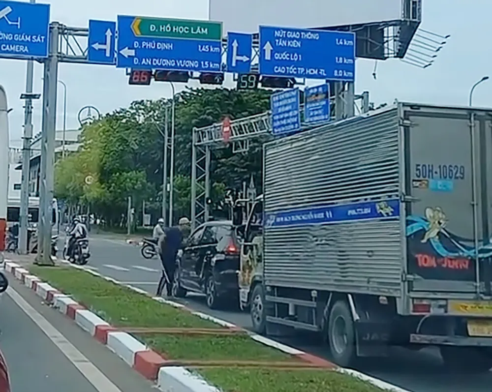 Hình ảnh ông N đỗ xe, cầm tuýp sắt dài "hùng hổ" với tài xế xe 7 chỗ đang dừng đèn đỏ. Ảnh cắt từ clip Xử phạt tài xế xe tải cầm tuýp sắt ‘hùng hổ’ trên đường Võ Văn Kiệt