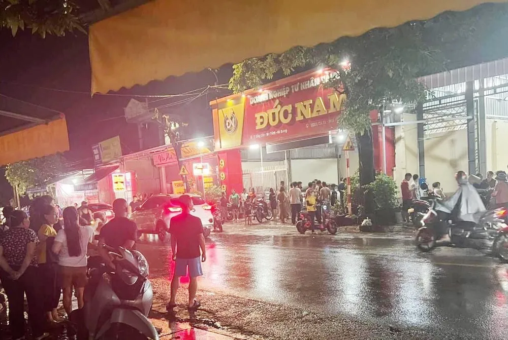 Người hiếu kỳ đứng giữa mưa quan sát tiệm vàng Đức Nam sau vụ cướp.