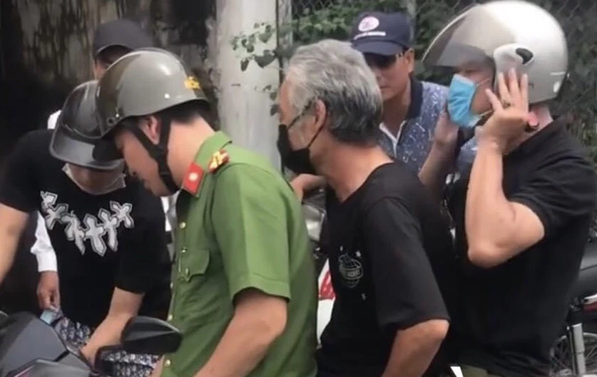 Đối tượng nghi vấn Trần Hữu Côn (tóc bạc, đeo khẩu trang đen) được công an áp tải về trụ sở sáng nay.