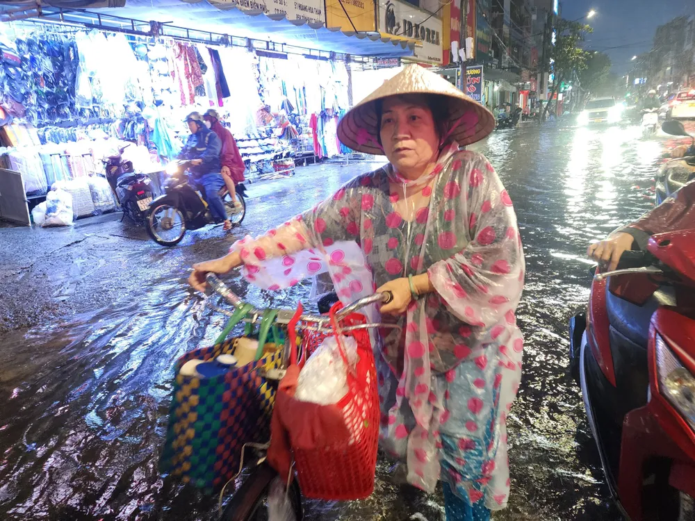 Tuy xe đạp không chết máy nhưng cũng không thể đạp qua đoạn đường Hùng Vương ngập sâu. Ảnh: MINH TRƯỜNG. cu ba di xe dap day xe met moi da nang.jpg