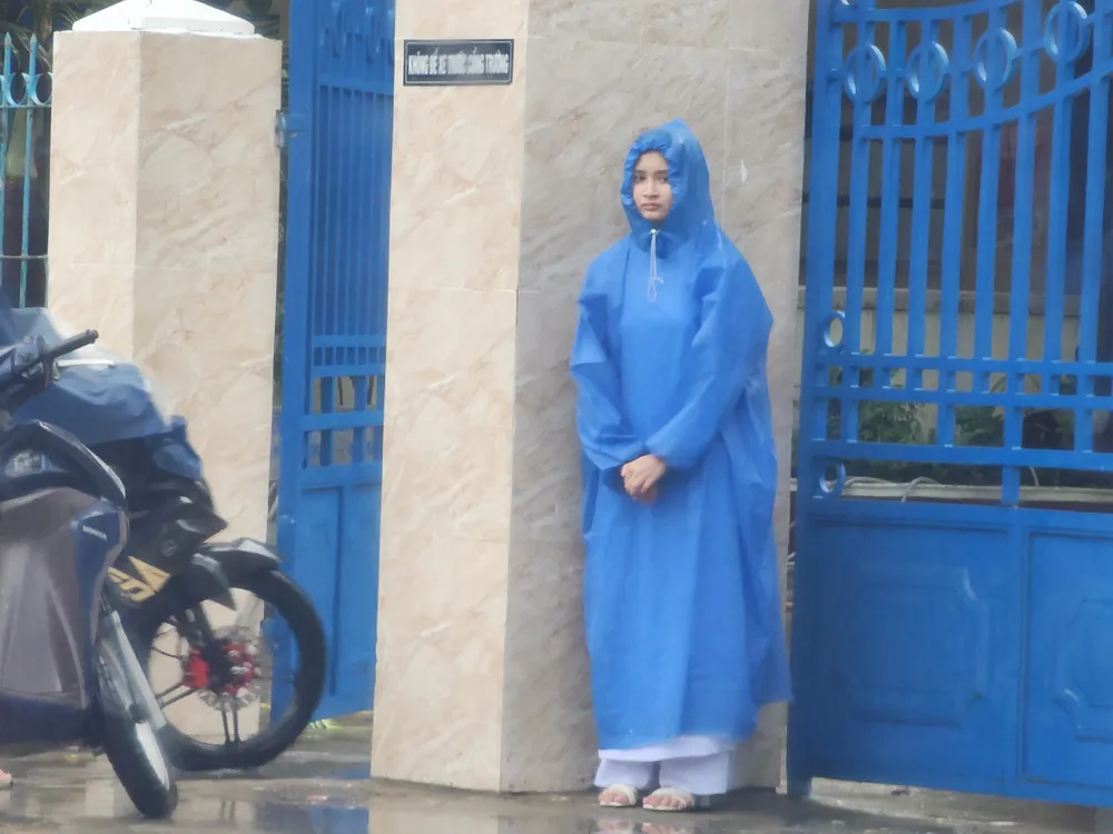 Học sinh chờ phụ huynh đến đón do mưa lớn. Ảnh: MINH TRƯỜNG. da nang mua lon hoc sinh cho don.jpg