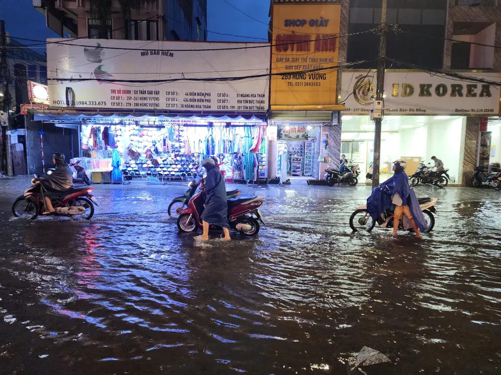 Dòng người mệt mỏi đẩy xe máy về nhà sau khi vượt ngập bất thành. Ảnh: MINH TRƯỜNG. xe may day bo hung vuong da nang.jpg