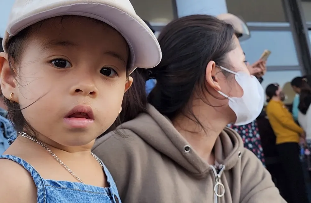 Chị Yến Nhi (19 tuổi) ôm đứa con nhỏ đứng ngoài hội trường ngóng chờ để được gặp mặt người chồng. "Nghe tin chồng em và bố chồng bị lật thuyền ngoài biển xa mà em lo sợ, trời còn mưa lớn làm em không biết phải hy vọng vào phép màu nào nữa. Giờ biết chồng và ba sống em vui lắm", chị Nhi chia sẻ trong nước mắt. Ảnh: MINH TRƯỜNG. dua be cung me cho ba.jpg