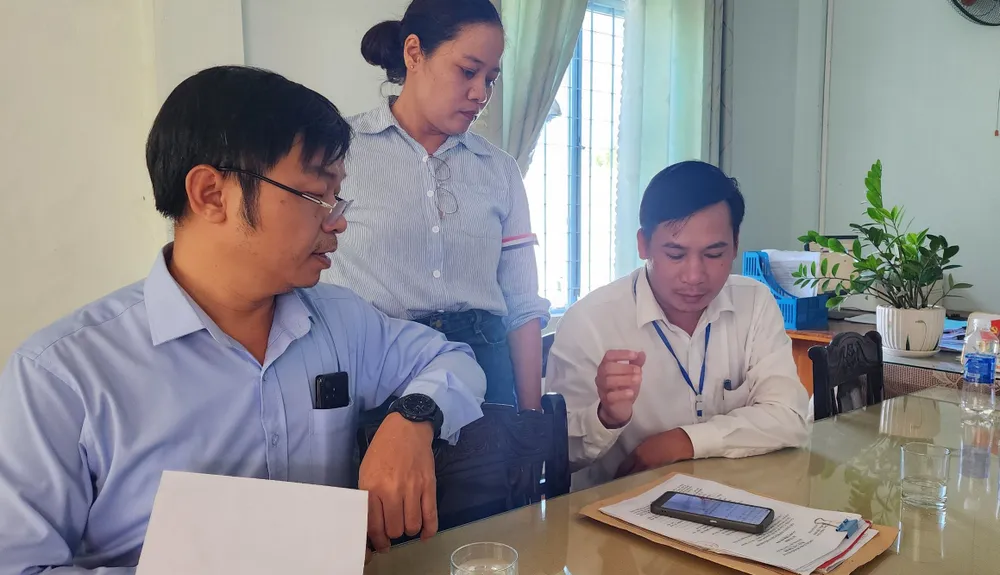 Ông Nguyễn Chí Trí, Chủ tịch UBND xã Hoà Khương (ngoài cùng bên phải) cùng hai cán bộ xã khẳng định con dấu có nghi vấn làm giả bởi nhiều điểm khác nhau bất thường. Ảnh: MINH TRƯỜNG. lanh-dao-xa-kiem-tra.jpg