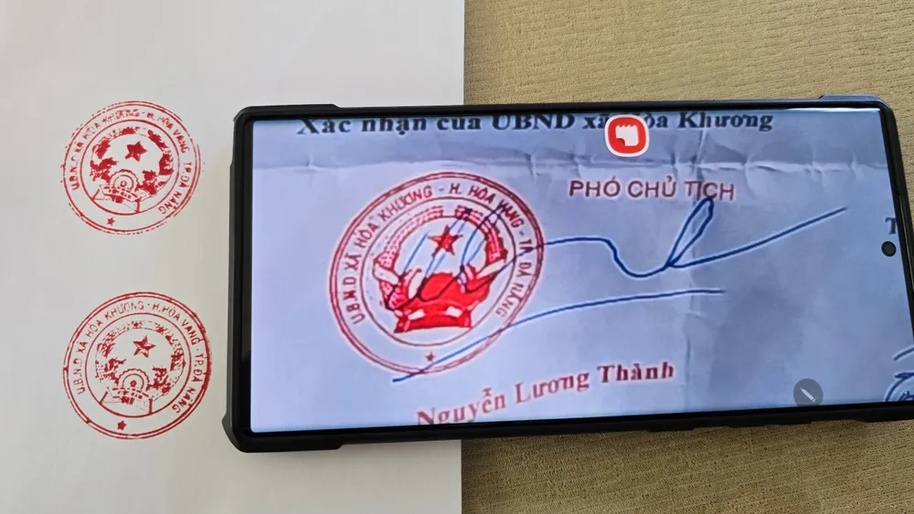 UBND xã Hoà Khương đóng thử con dấu lên giấy trắng để so sánh khác biệt với con dấu (bên trong điện thoại) nghi được làm giả. Ảnh: MINH TRƯỜNG. so-sanh-con-dau-gia-cap-giay-phep-phong-chay-chua-chay.jpg
