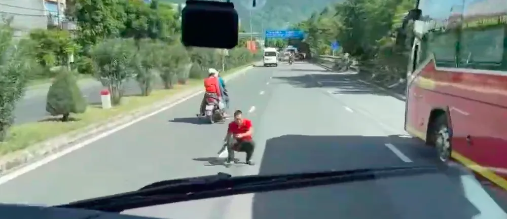 Người đàn ông ngồi xuống chắn ô tô giữa đường