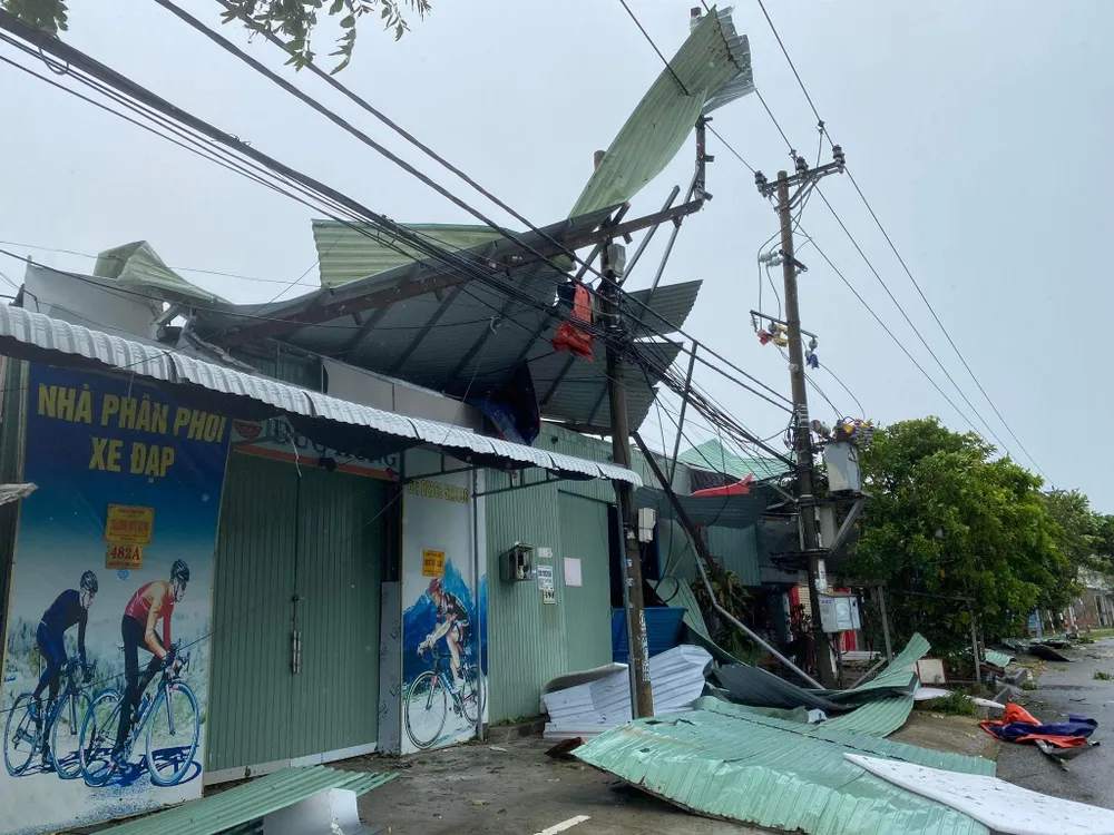 Một căn nhà bị tốc mái, mái tôn nằm vắt vẻo trên trụ điện. Ảnh: HẢI HIẾU