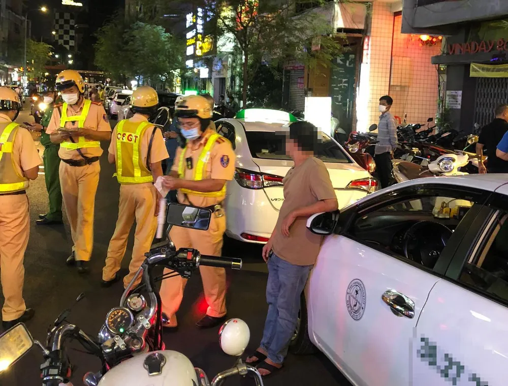 CSGT kiểm tra với các xe taxi dù đậu ở khu vực xung quanh phố đi bộ Bùi Viện. Ảnh: ĐC kiem-tra-taxi-du-tphcm