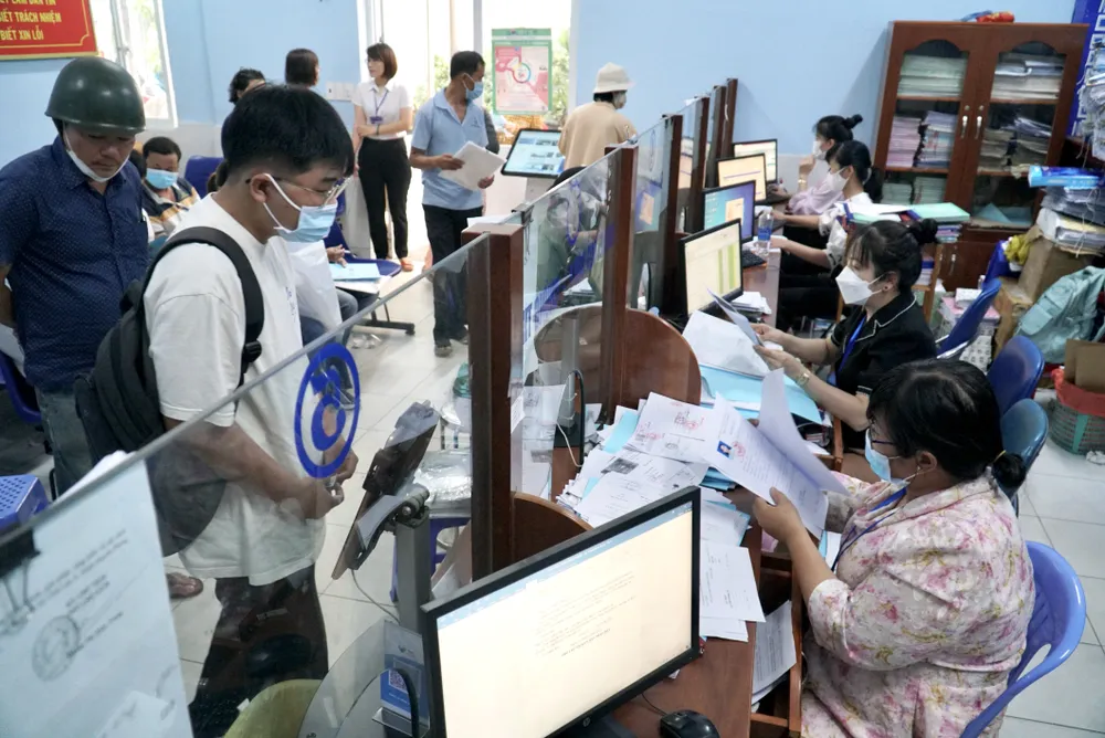 Người dân đến làm hồ sơ tại bộ phận một cửa UBND phường Vĩnh Lộc A, huyện Bình Chánh. Ảnh: BẢO PHƯƠNG cán-bộ-phường-đông-dân