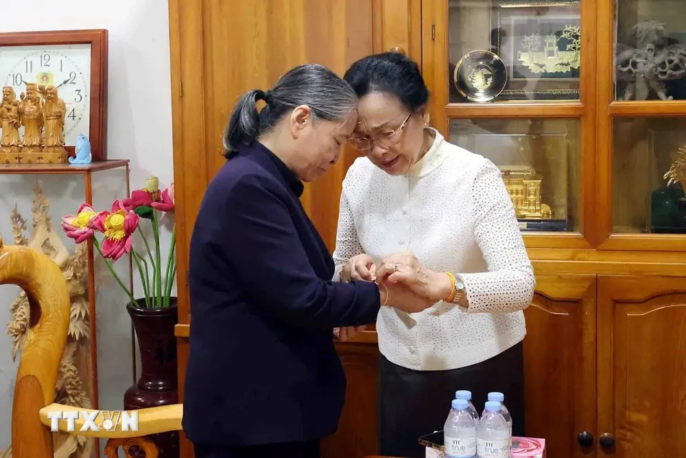 Bà Naly Sisoulith, Phu nhân Tổng Bí thư, Chủ tịch nước Lào Thongloun Sisoulith buộc chỉ cổ tay chúc may mắn, bình an tới bà Ngô Thị Mận, Phu nhân cố Tổng Bí thư Nguyễn Phú Trọng. Ảnh: TTXVN phu-nhan-naly-sisoulith-tham-phu-nhan-co-tong-bi-thu-nguyen-phu-trong (2).jpg